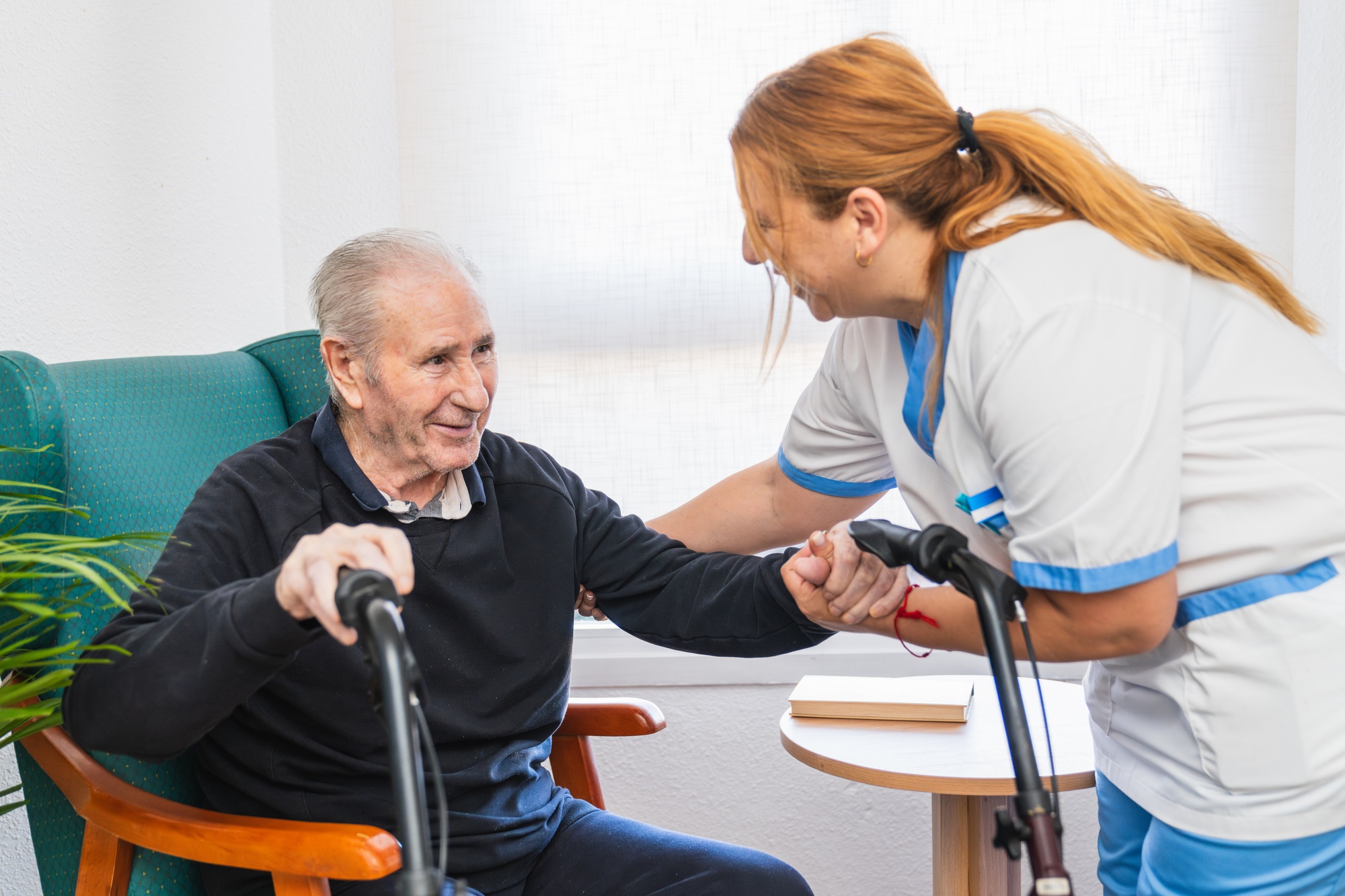 Caring nurse assisting elderly man in nursing home