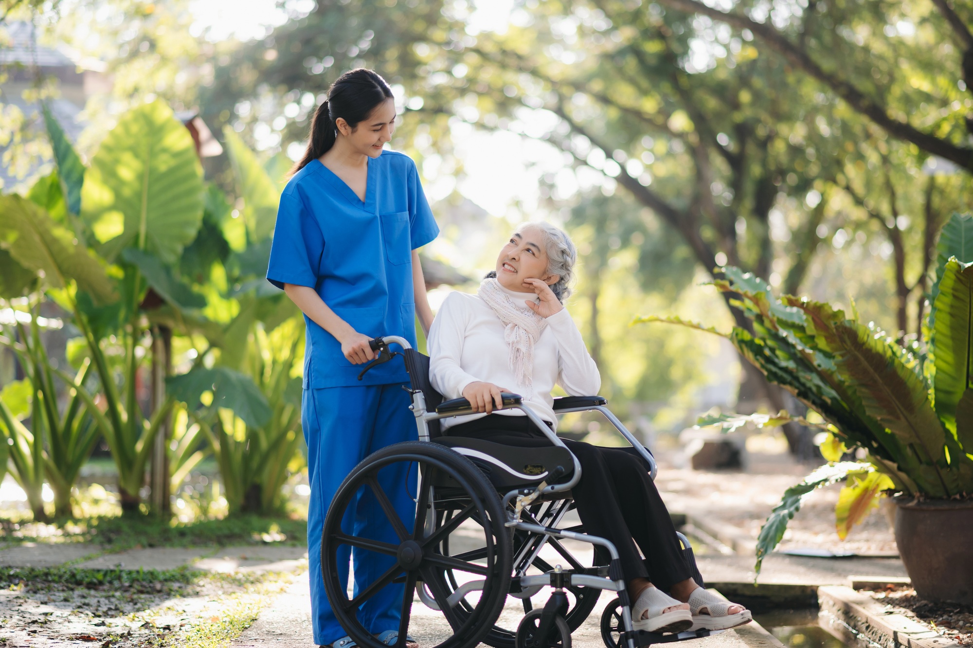 Elderly asian senior woman on wheelchair with Asian careful caregiver and encourage patient